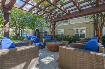 A patio with brown wicker furniture and a wooden pergola.